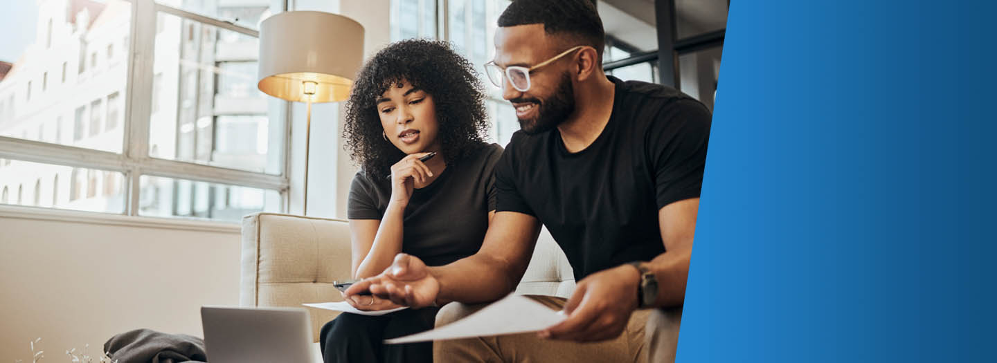 Man and woman sitting on couch looking over finances